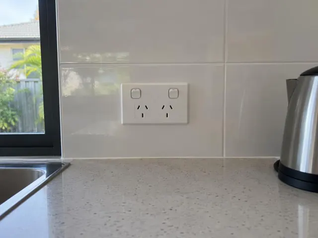 Double power point on a tiled kitchen splashback beside a sink and kettle in Broadbeach