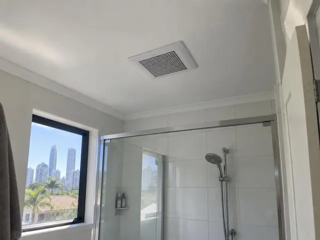 Bathroom ceiling exhaust fan above a tiled shower in a modern bathroom with city view in Surfers Paradise